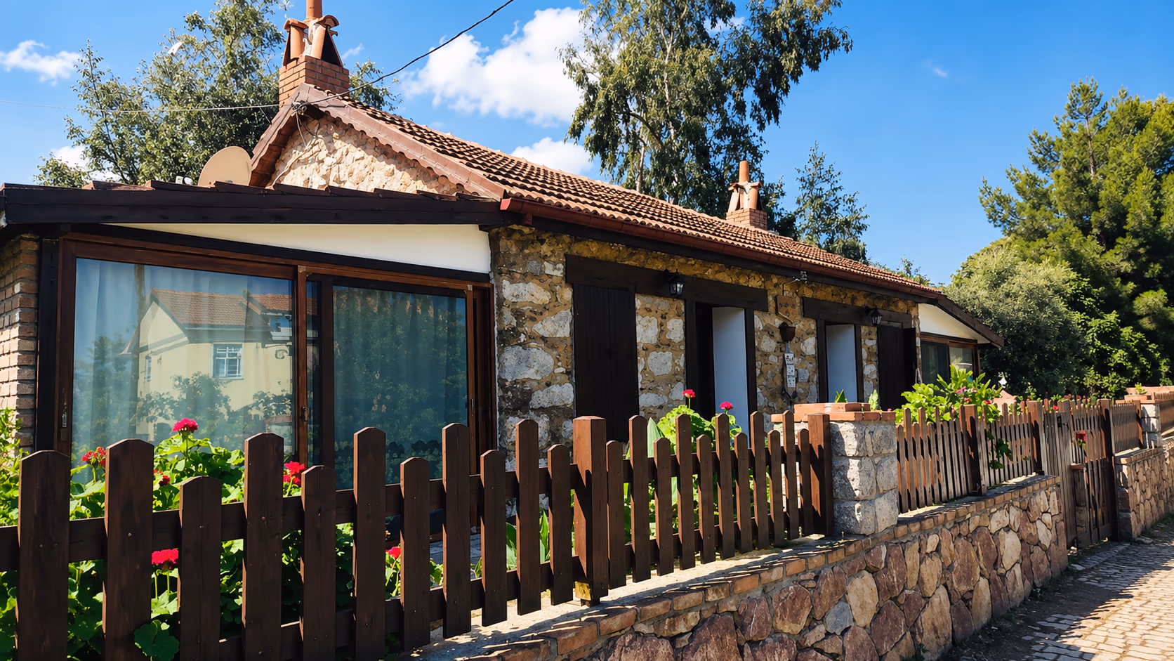Selimiye Taş Ev — sardunyalı bahçe çiti önünde taş köy evi